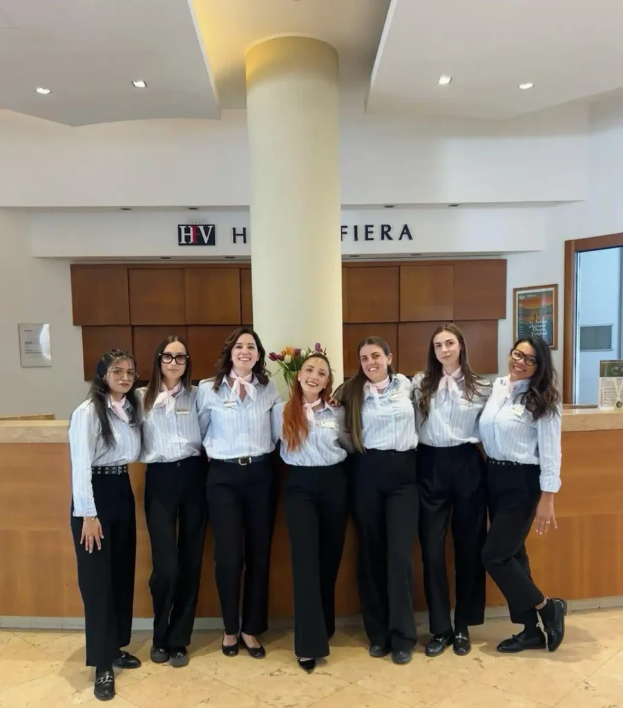 Nell'immagine, lo staff tutto al femminile dell'Hotel Fiera Verona, che sorride davanti al bancone della Reception.