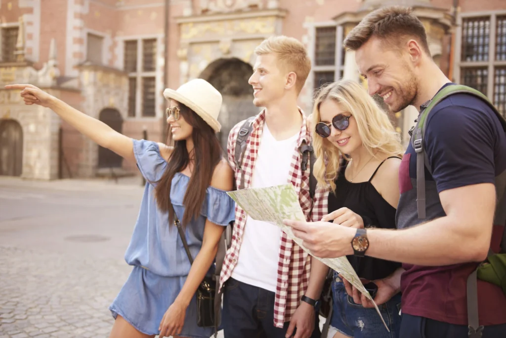 In the image, a group of four boys are looking at the map while visiting a city.
